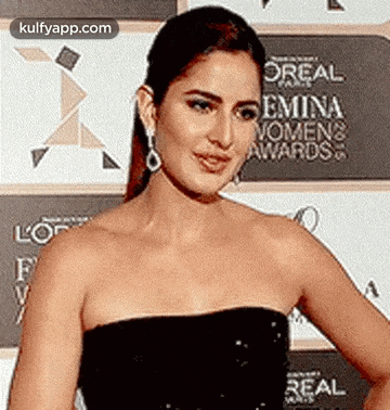 a woman in a strapless dress is standing on a red carpet .