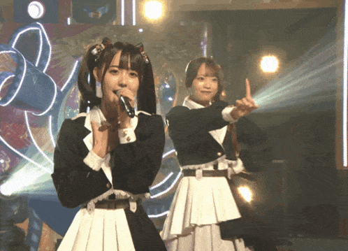 a girl singing into a microphone while another girl points