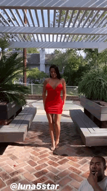 a woman in a red dress is standing in front of a white pergola