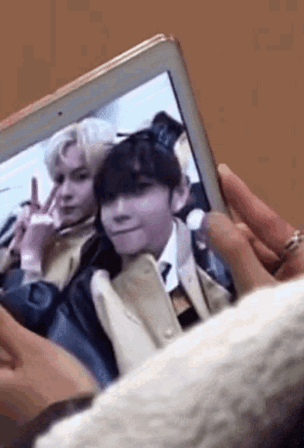 a person is taking a picture of two men on a tablet .