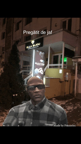 a man wearing sunglasses stands in front of a building that has a sign that says ella bijou
