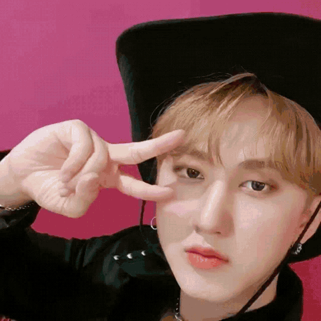 a young man wearing a cowboy hat is giving a peace sign