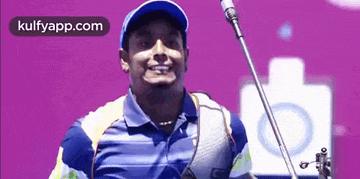 a man is holding a bow and arrow in front of a purple background .