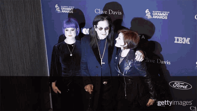 a group of people posing for a picture in front of a blue wall that says clive davis
