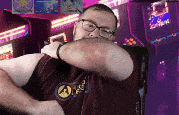 a man wearing glasses and a shirt that says ale is covering his mouth