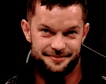 a close up of a man with a beard smiling in a dark room .