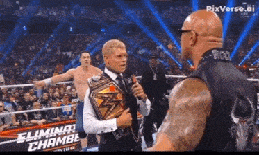 a man in a suit is holding a wrestling belt and talking to a man in a black vest