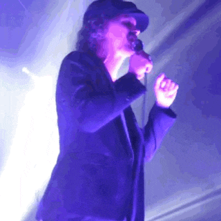 a man is singing into a microphone in a dark room