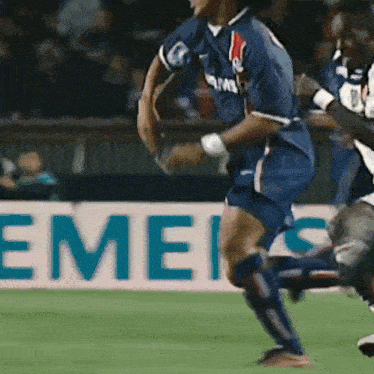 a soccer player in a blue uniform is running on the field in front of a siemens sign