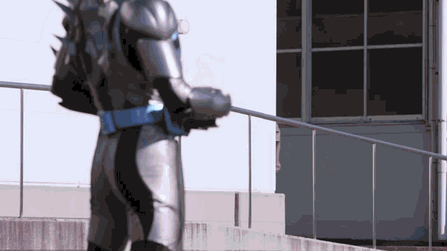 a man in a superhero costume is standing next to a railing .