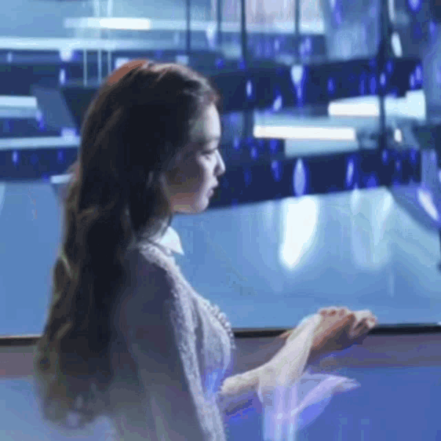 a woman with long hair is standing in front of a blue wall
