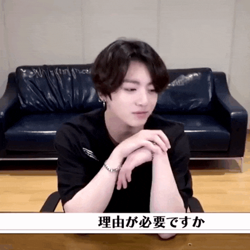 a man in a black shirt is sitting in front of a couch with chinese writing on it