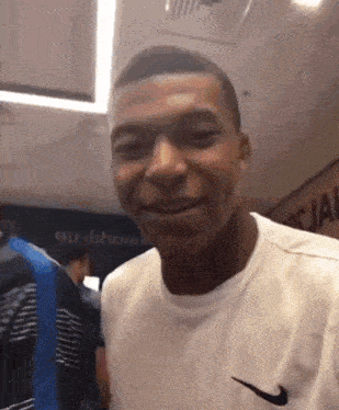 a man wearing a white nike shirt is smiling in a room
