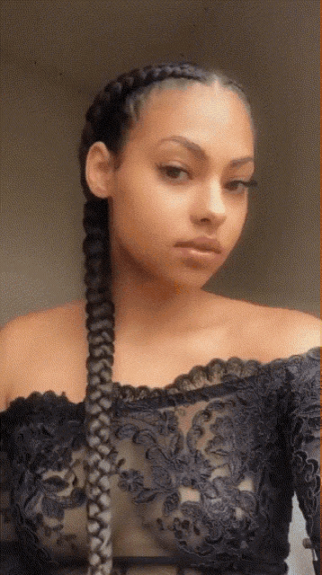 a woman with braids in her hair is wearing a black lace top