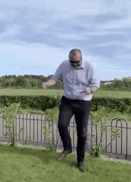a man in a white shirt and black pants is dancing in a grassy field .