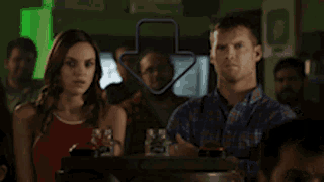 a man and a woman are sitting in a bar with an arrow pointing to the man