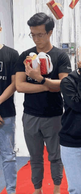 a man in a black shirt with the word pei on it holds a gift