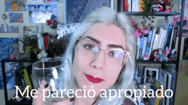 a woman wearing glasses holds a glass in front of a sign that says me parecio apropiado