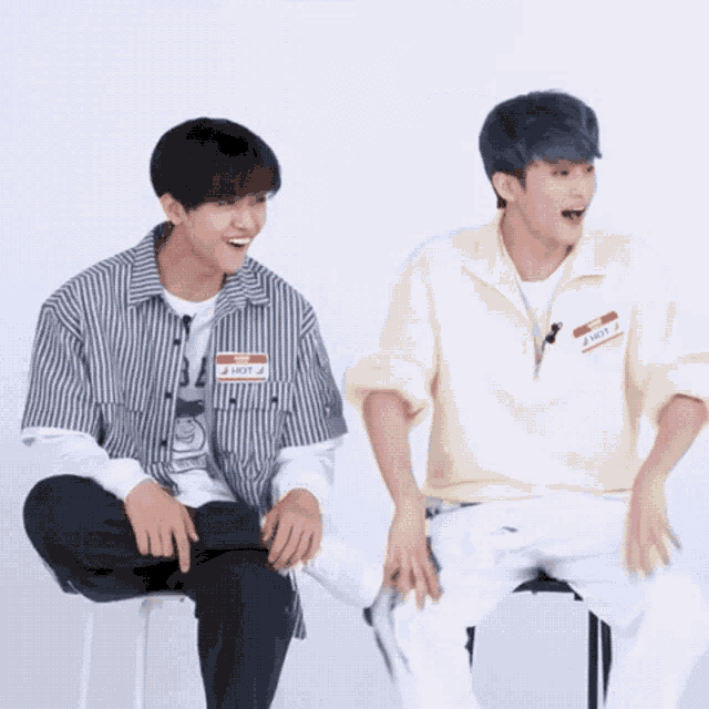 two young men are sitting next to each other with one wearing a name tag that says hot
