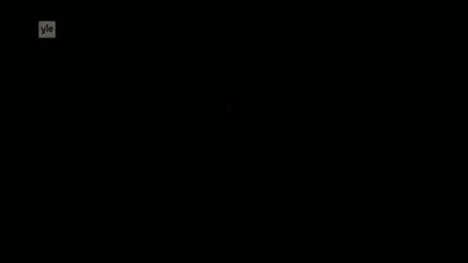 a man in a white robe is standing next to a bed with a green light behind him .