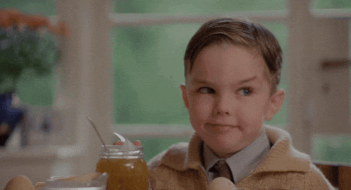 a young boy is sitting at a table with a jar of honey and eggs