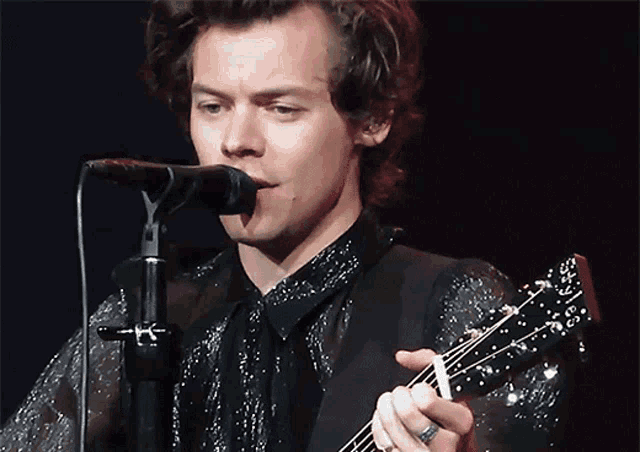 a man is playing a guitar and singing into a microphone