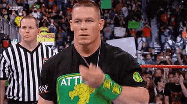 a wrestler is standing in a ring with a referee .