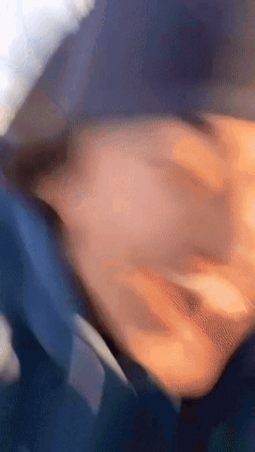 a blurry picture of a person 's face with a blue jacket on