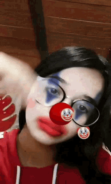 a woman wearing glasses and a red nose with a smiley face on it