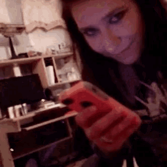 a woman is taking a selfie with her cell phone in a room .