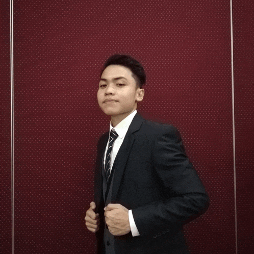 a young man in a suit and tie poses for a picture