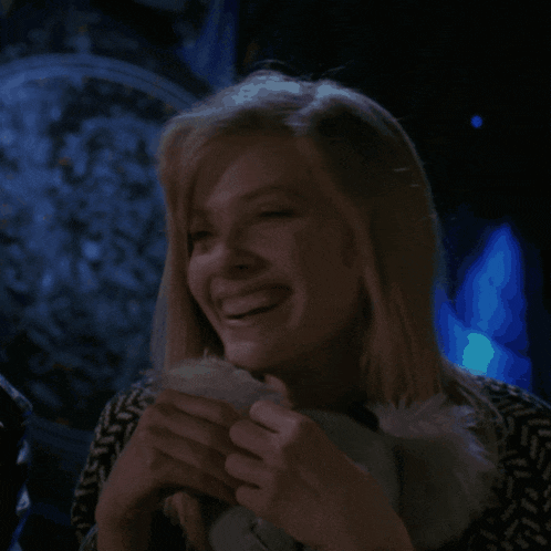 a woman is smiling in a dark room with a clock in the background