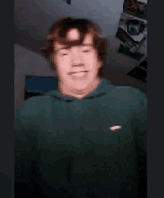 a blurry picture of a man in a green hoodie smiling