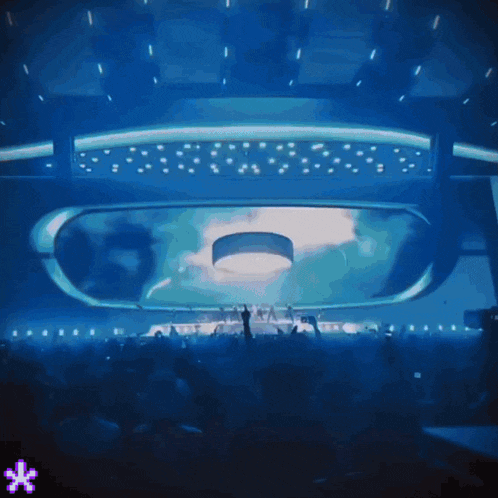 a crowd of people are gathered in a dark room with a blue light coming out of the ceiling