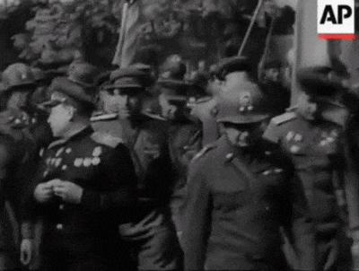 a black and white photo of a group of soldiers in uniform standing in a line .