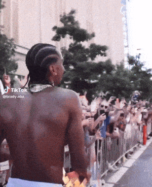 a man without a shirt is standing in front of a crowd of people with a tiktok watermark on his back