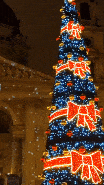 a very tall christmas tree with red and blue bows