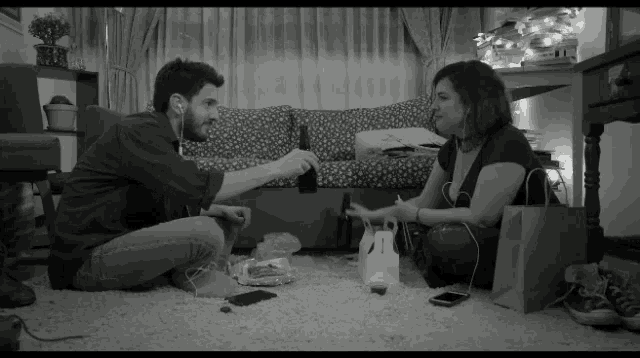 a man and a woman are sitting on the floor in a living room