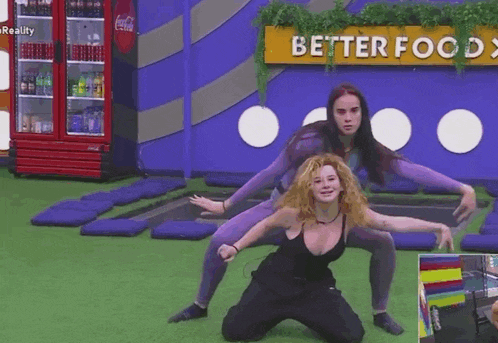 two women are doing yoga in front of a better food sign