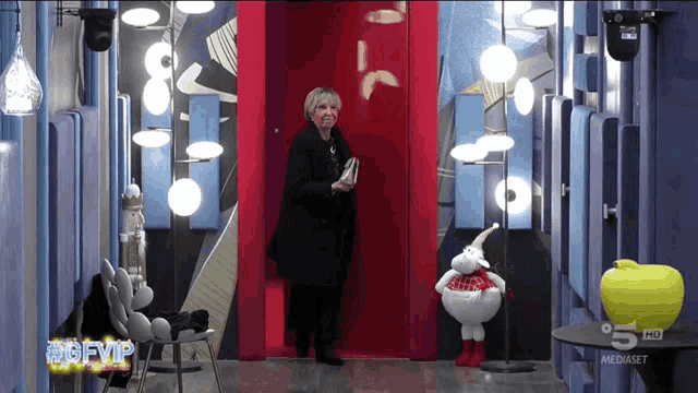 a woman stands in front of a red door that says 5 hd