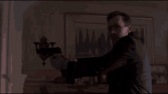 a man in a suit and tie is standing in a dark room holding a flashlight .