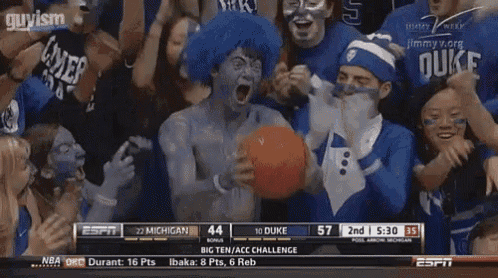 a man with blue paint on his face is holding a basketball in front of a crowd