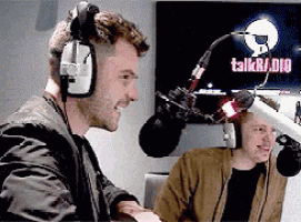 a man wearing headphones is talking into a microphone in front of a talkradio screen
