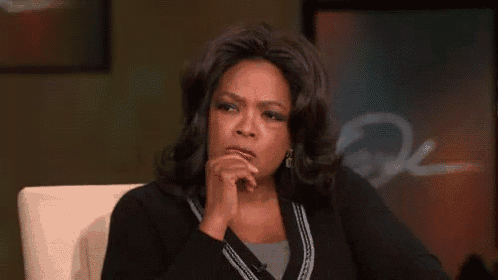 oprah winfrey is sitting in a chair with her hand to her chin .