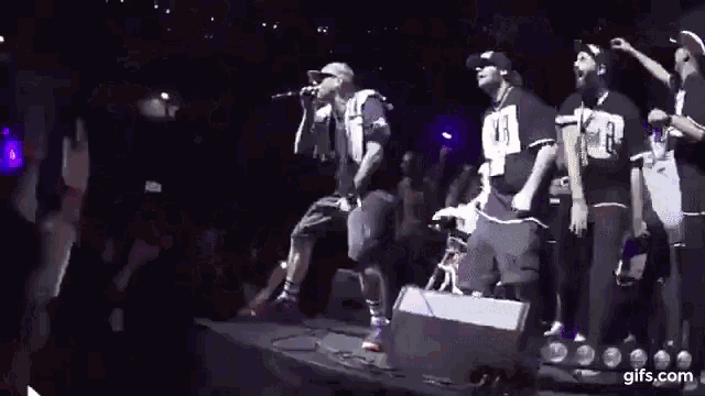 a group of men are standing on a stage holding microphones .