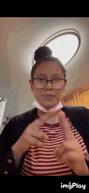 a woman wearing glasses and a mask is making a peace sign with her hands