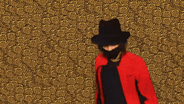 a man wearing a black hat and a red jacket is standing in front of a gold background