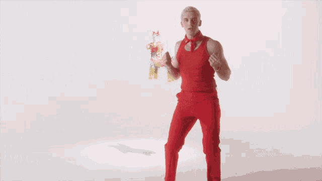 a man in a red tank top and red pants is dancing in front of a pinata