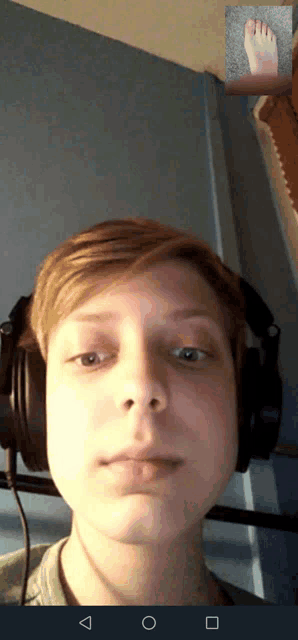 a young man wearing headphones is looking at a picture of his foot
