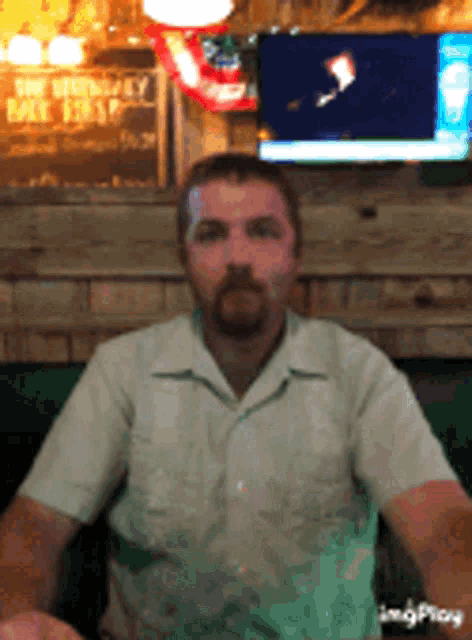 a man with a beard is sitting in front of a sign that says ' you won 't have beer '